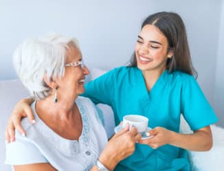 a caregiver and a senior woman smiling