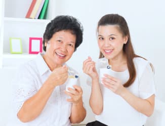 snior woman and a caregiver smiling while drinking