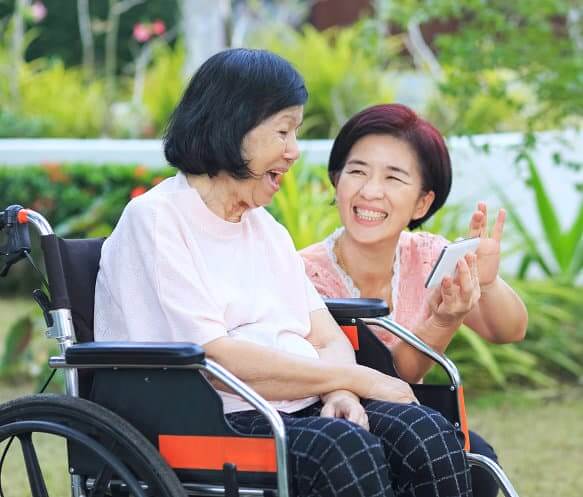 caregiver assisting senior woman in operating a cellphone