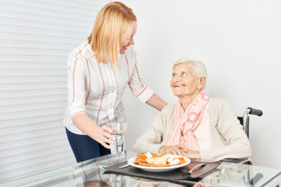 nursing lady serves old woman a meal in a nursing home or at home