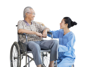 men sitting on wheelchair while talking and smiling with his nurse