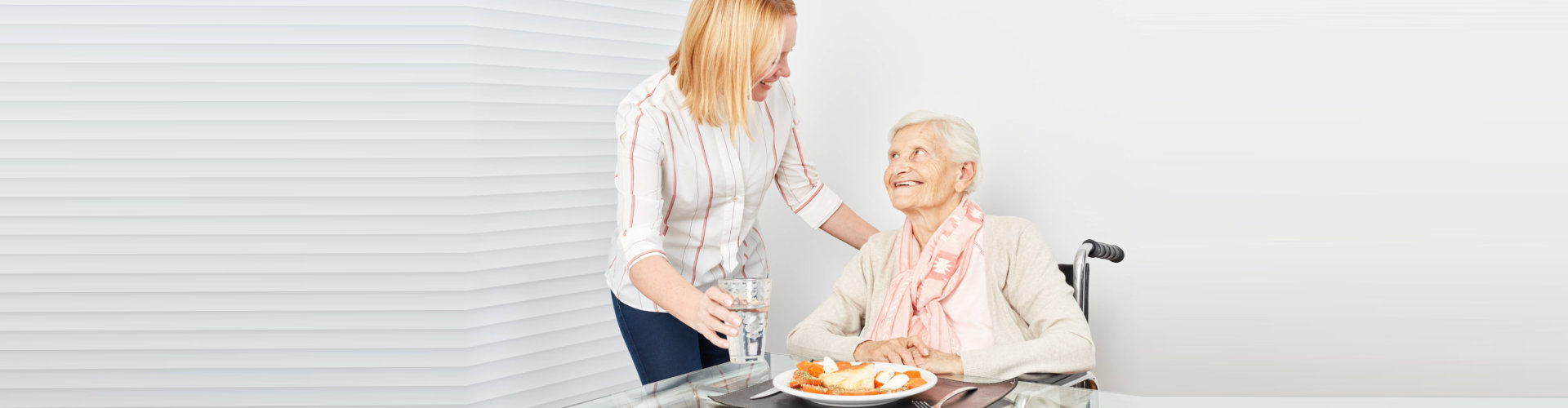 nursing lady serves old woman a meal in a nursing home or at home